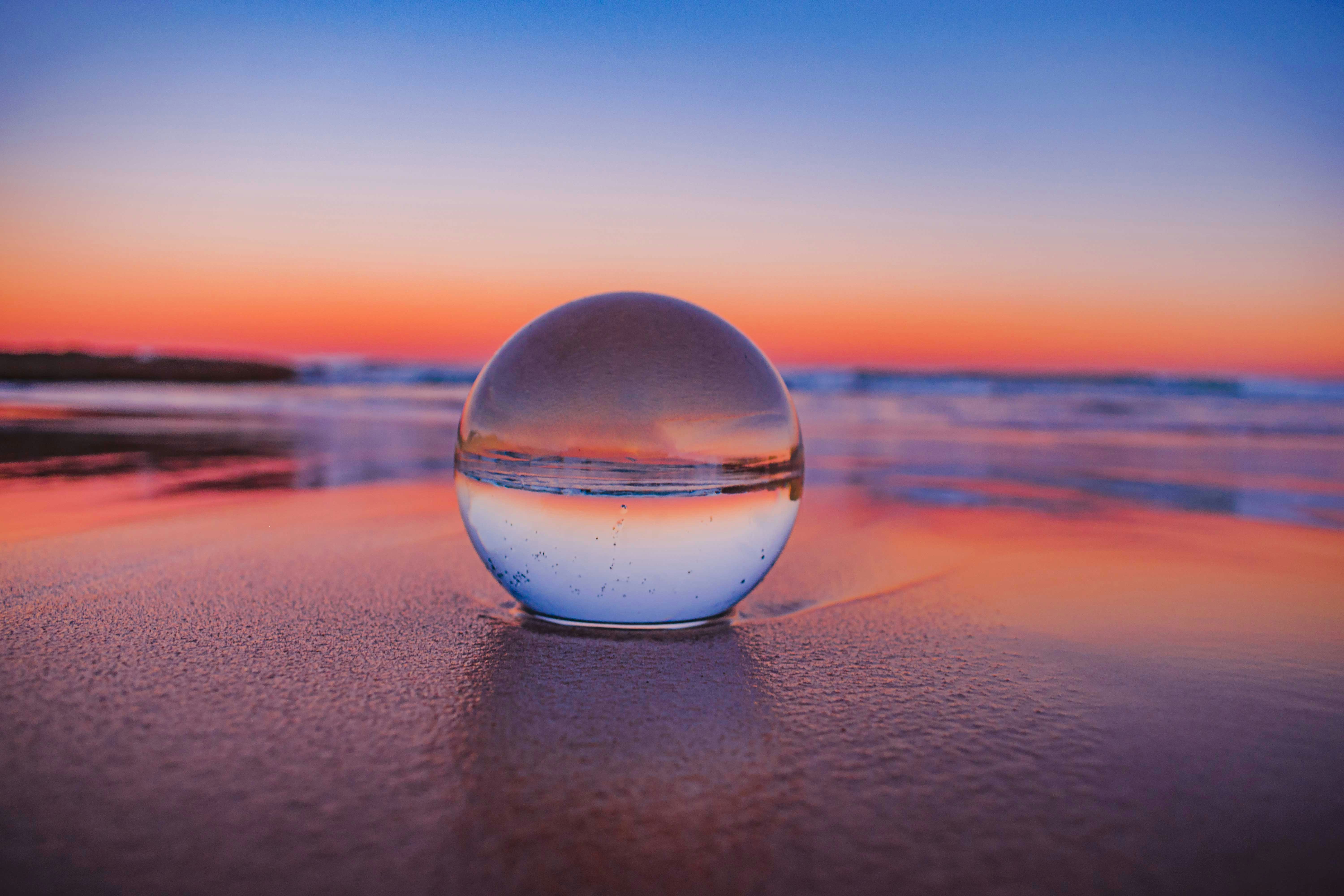 A glass sphere held at a sunset horizon, representing a fund held in balance